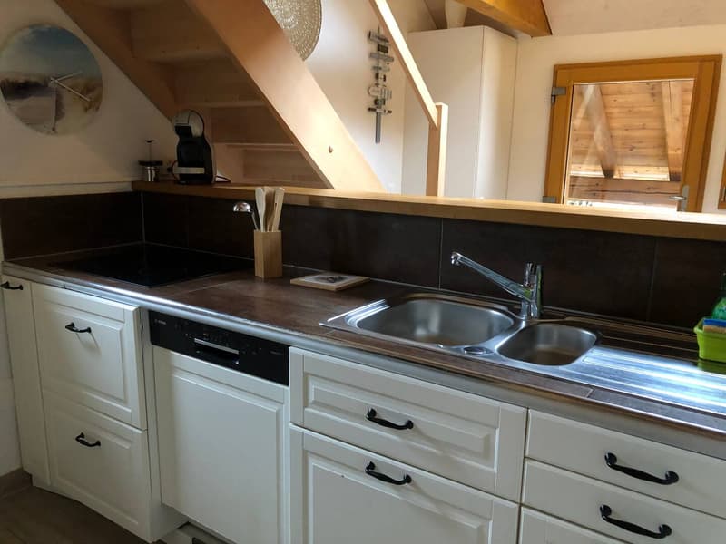 White cabinets, wooden countertops, stainless steel sink, dishwasher, black induction hob, wooden ceiling beams