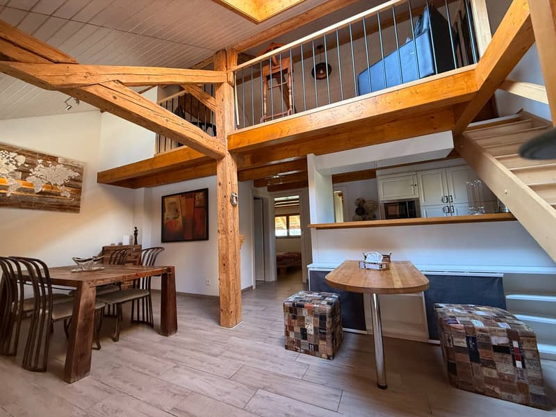 Wooden beams, table, chairs, stools, microwave, open staircase