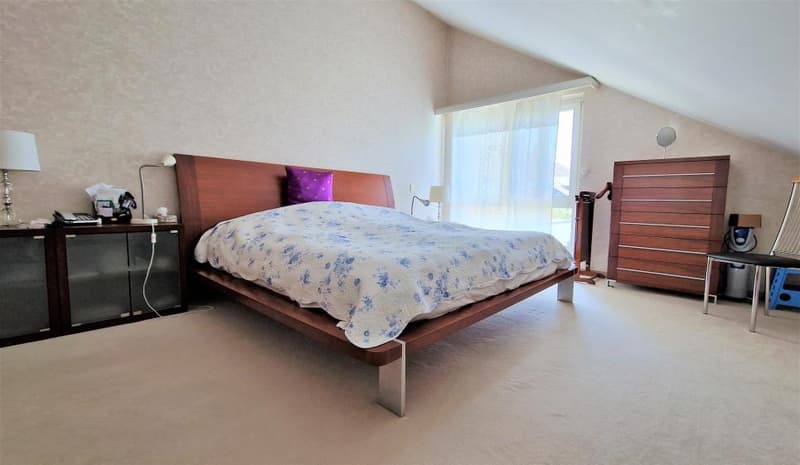 Spacious bedroom with a large bed, wooden furniture, and a window providing natural light.