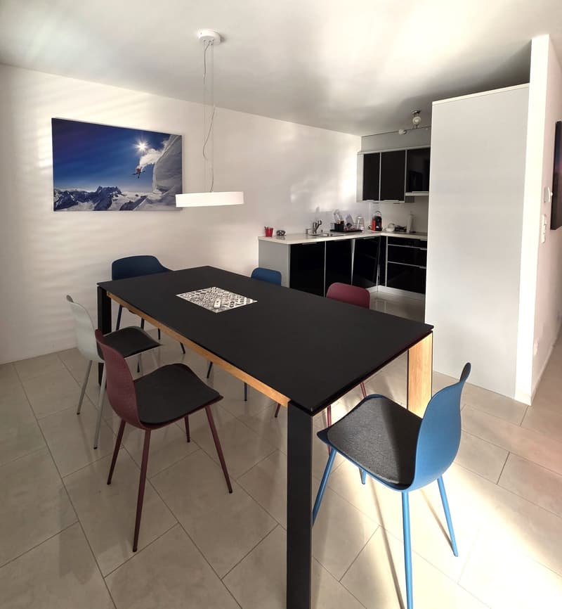 Dining room, long black dining table, 6 chairs, modern kitchen, photo hanging on the wall