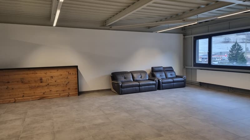 tiled floor, wooden reception desk, two black sofas, a large window