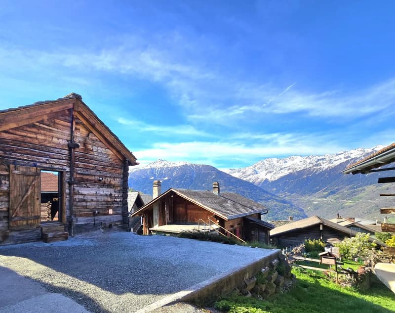 Wooden chalet, gravel driveway, wooden door, mountains in the background