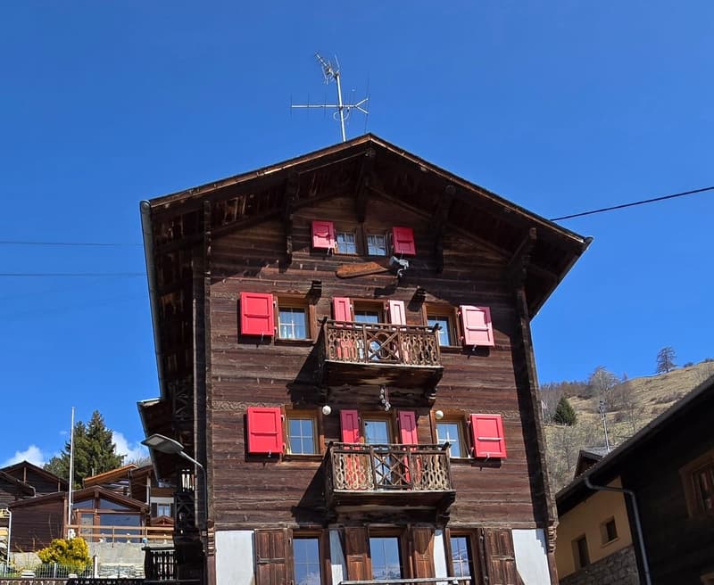 3 story wooden house, red shutters, balconies, antenna on the roof
