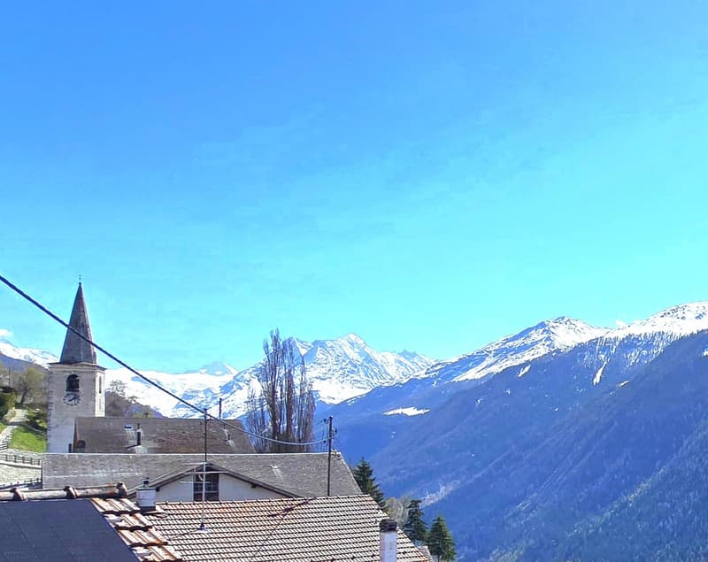 House with tiled roof, steeple, mountains in the background