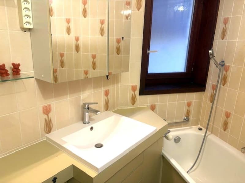 Bathroom with white sink, bathtub, mirror, and tiled walls with floral patterns.