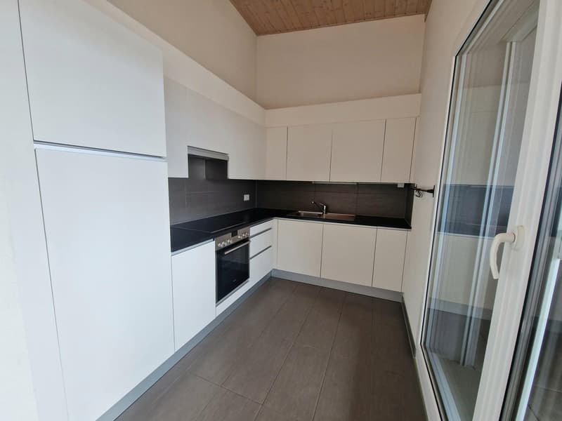 Modern kitchen with white cabinets, black countertops, and tiled flooring. The kitchen includes a built-in oven and dishwasher.