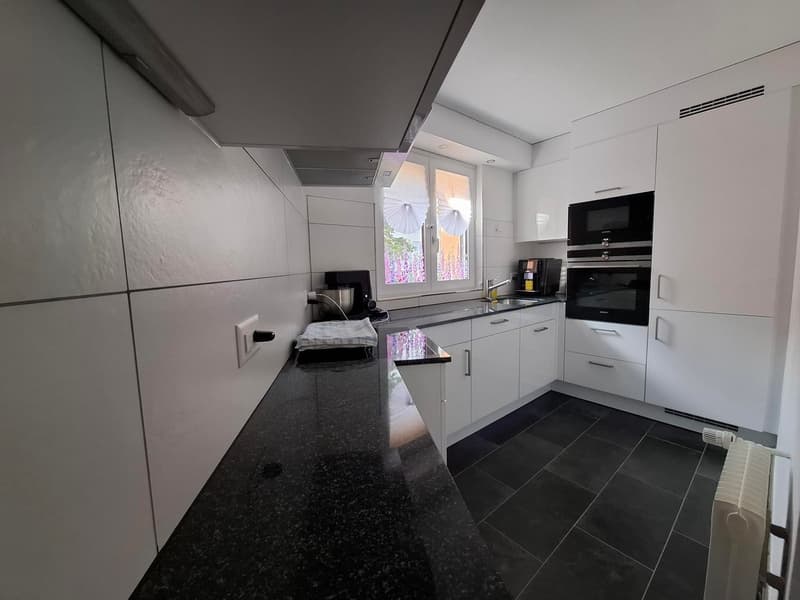 kitchen, black countertop, white cabinetry, double oven, dishwasher, sink, faucet, window, curtains, electric kettle