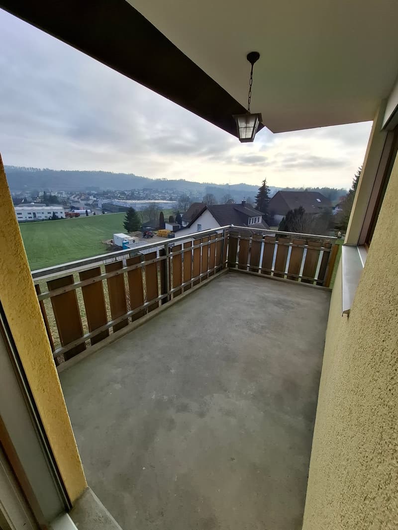 Balcony with wooden railings, concrete floor, view of the landscape