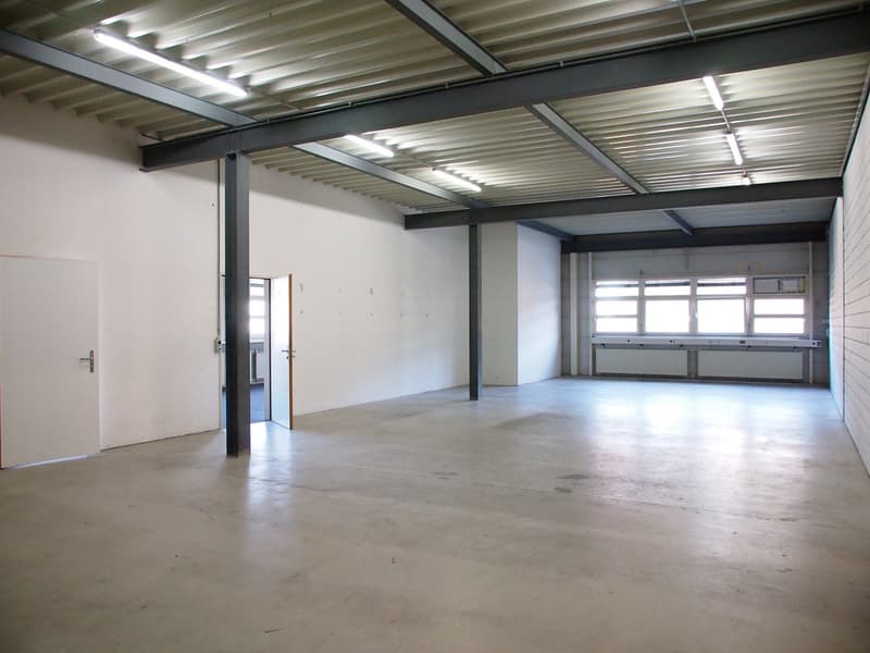 large open space, metal beams, white walls, open doors, concrete floor, windows