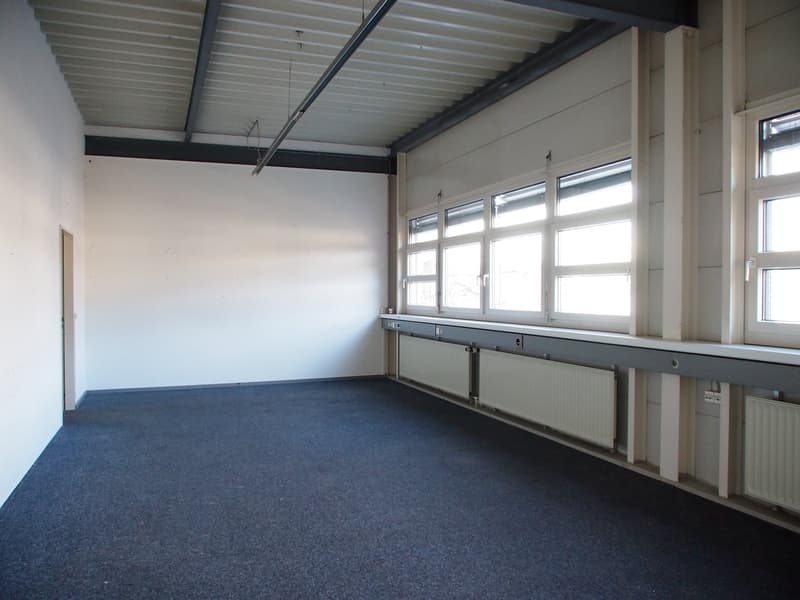 empty room, white walls, large windows, metal beams in ceiling, radiators, carpeted floor