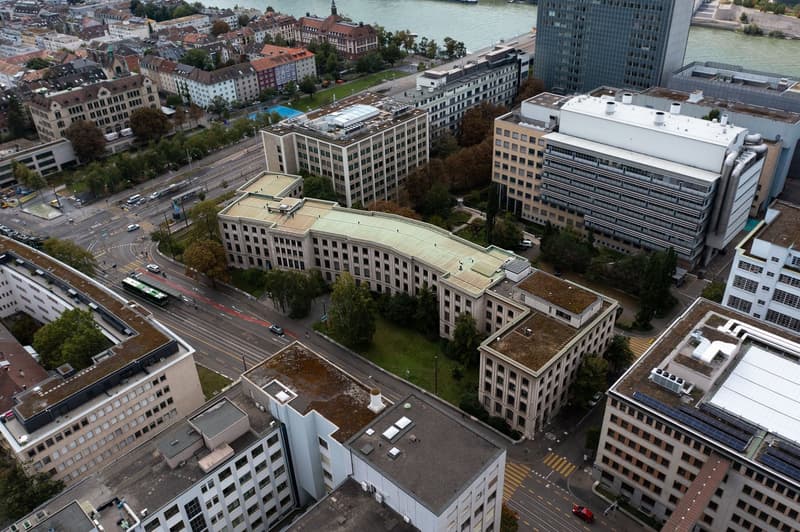 Multiple high-rise buildings, green rooftops, windows, visible solar panels, roads, vehicles, trees, body of water