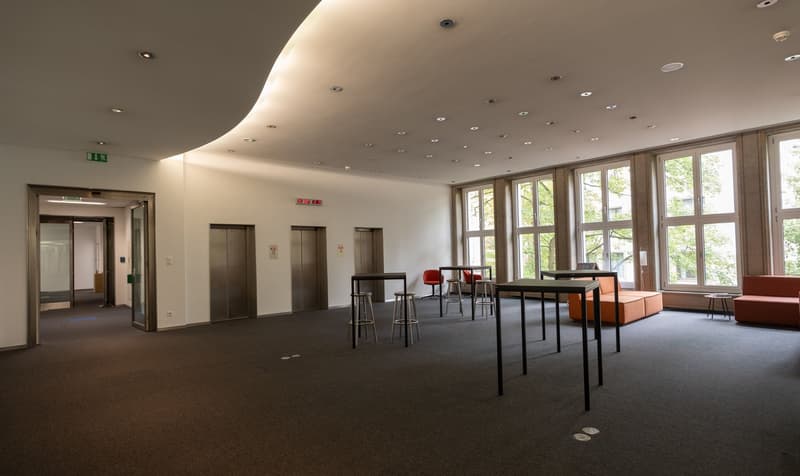 empty room with furniture, two elevators, multiple windows with view to outside