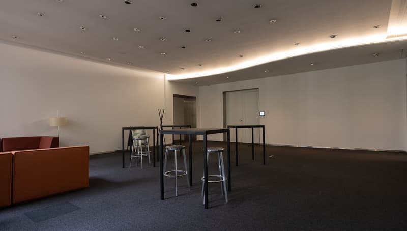 empty room with black tables, stools, sofa and a lamp