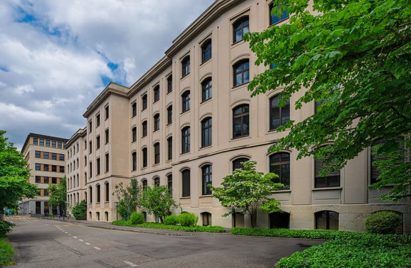 large beige building, many windows, landscaped garden, city street