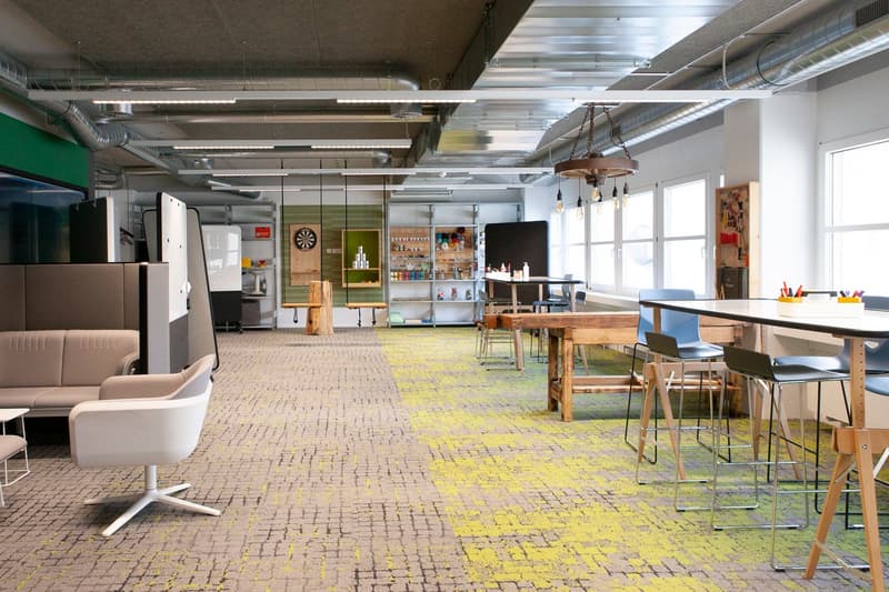 open plan with desks, chairs, tables, couch, flooring, and ceiling lights