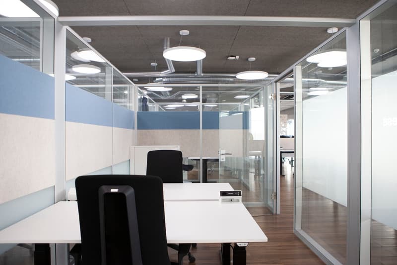 modern open office, white desks, black chairs, glass walls, wooden floor