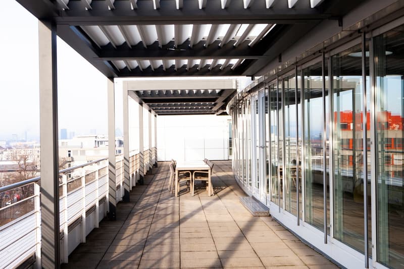 a spacious balcony, tables and chairs, a black awning