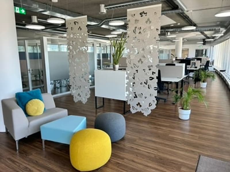 modern office with grey couch, blue table, yellow balls, white desk, wooden floor, potted plants