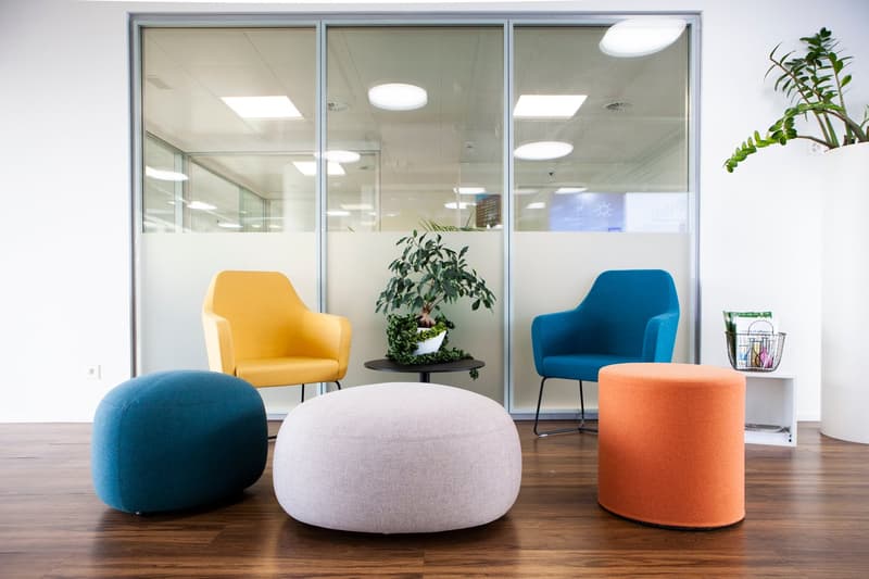 Wooden floor, several chairs, table, white walls, glass walls, plants