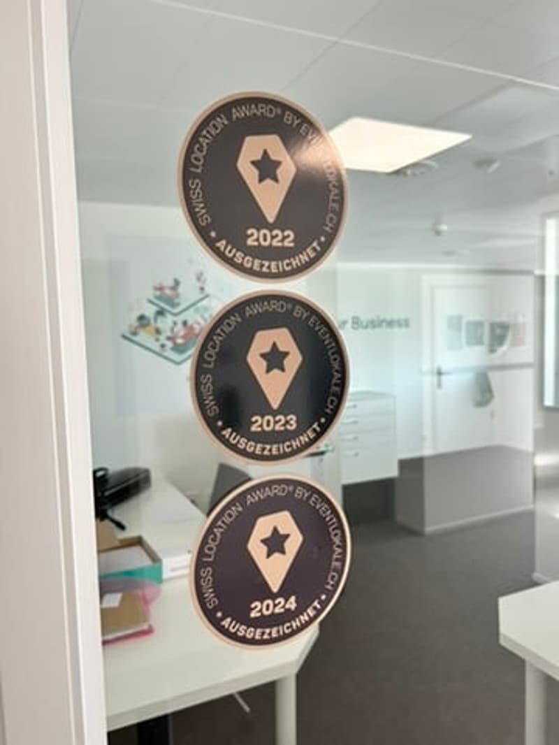 Awards displayed on a glass door, reflecting a room with desk and cabinets