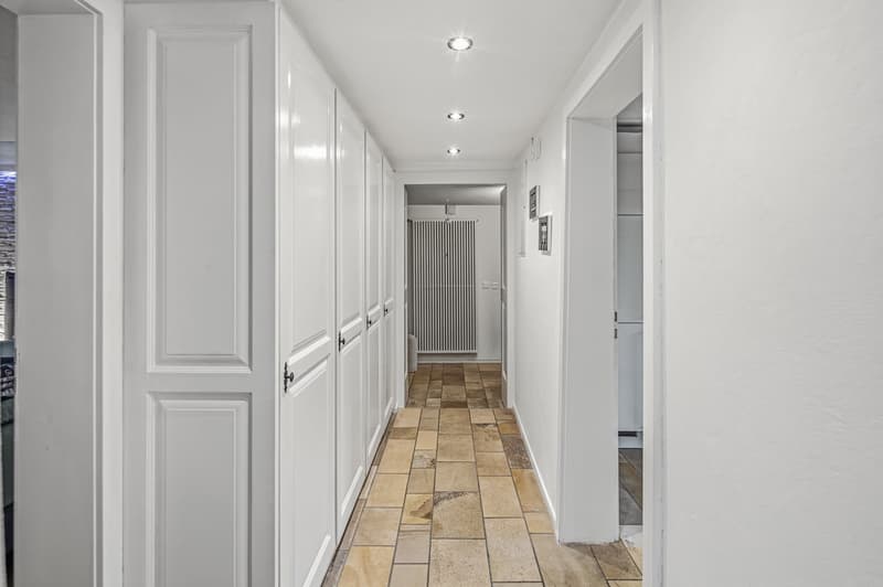 corridor with white doors, tiled floor, ceiling lights
