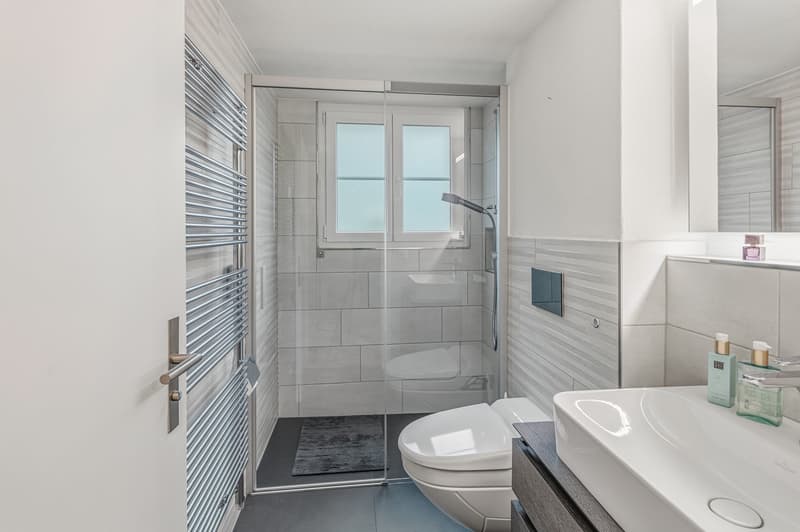 modern, white tiles, glass walk-in shower, white toilet, vanity with a sink, modern faucet, storage cabinet
