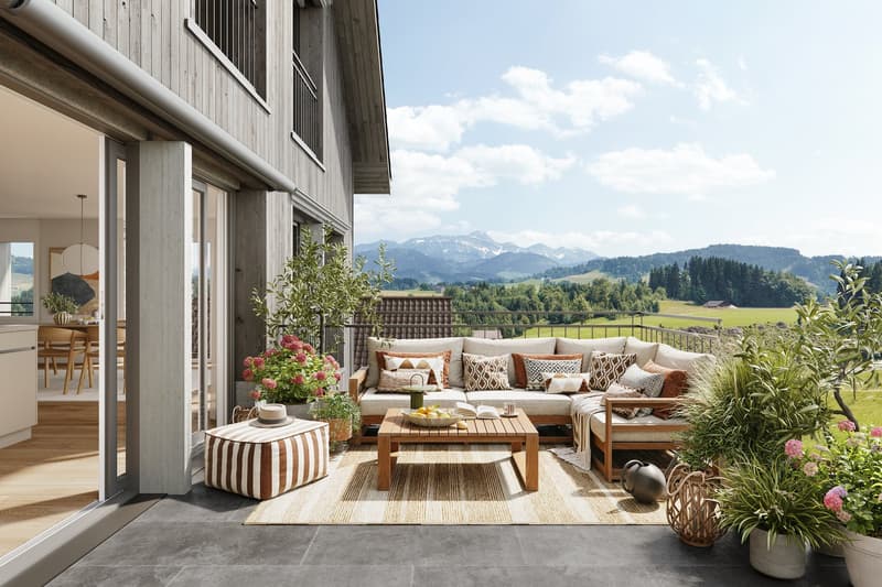 Spacious outdoor patio with wooden deck, comfortable seating area with sofa and armchairs, coffee table, decorative pillows, potted plants, and scenic mountain view in the background