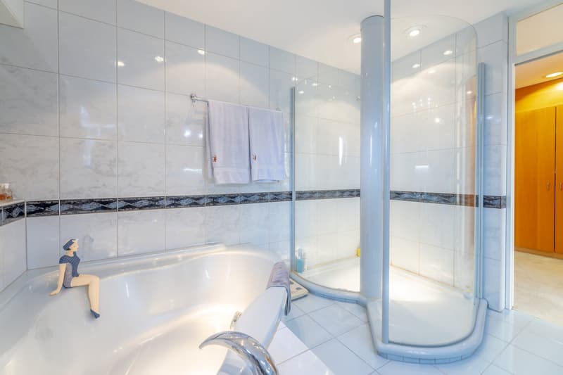 white tiles, bathtub, shower, wooden cabinet, towel rack