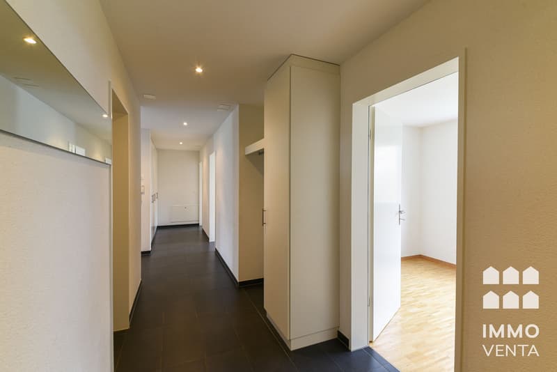 / a long corridor with white walls and a door in a modern house or apartment