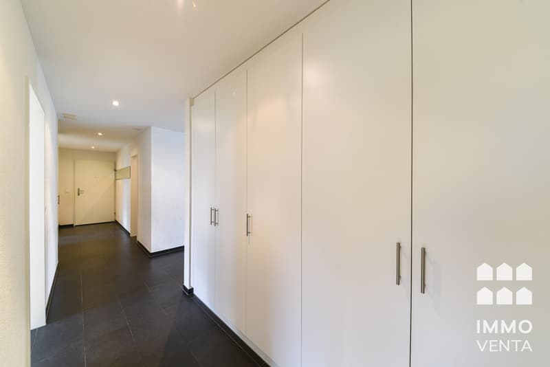 / a picture of a modern apartment with white walls and floors and a large walk - in closet in the hallway