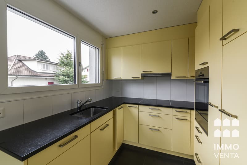 / a kitchen with yellow cabinets and a black counter
