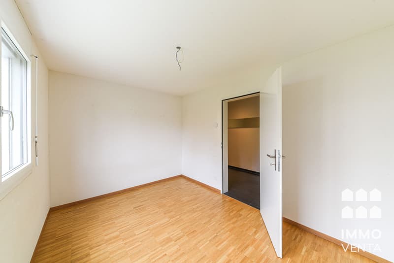 / an empty room with wooden floors, white walls and a large window