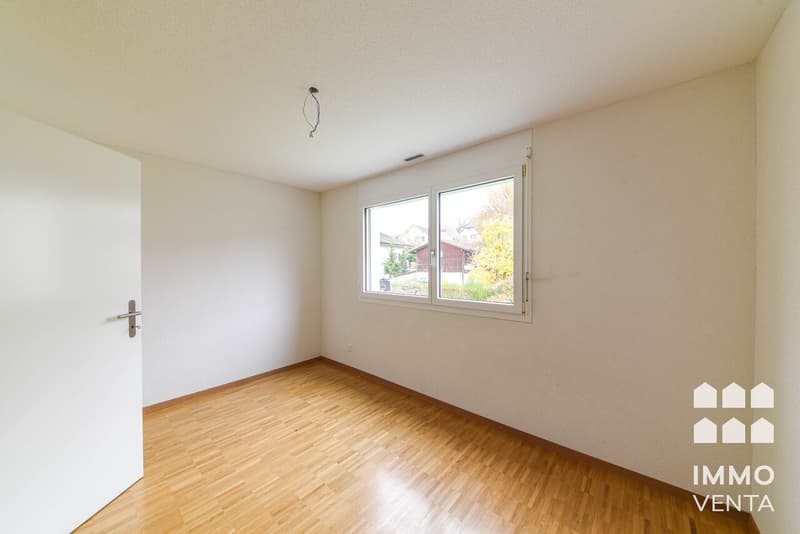 / an empty room with wood floors, white walls and a large window