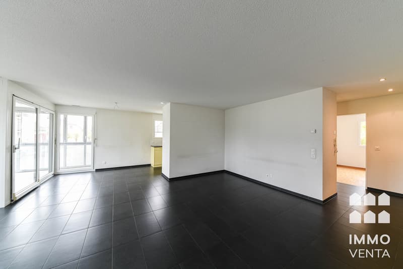 / an empty living room with black floors and a large sliding door