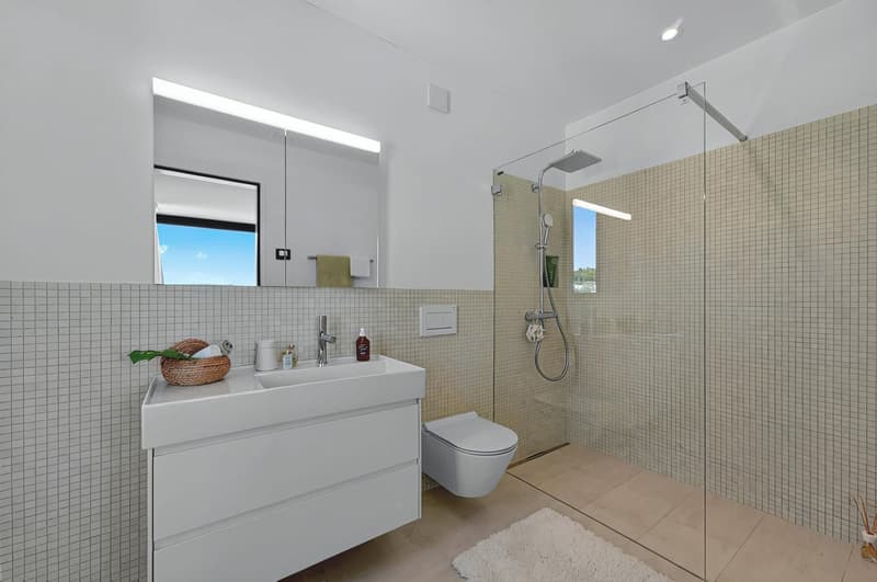 modern bathroom with white tile, white vanity, modern shower, toilet, towel rack