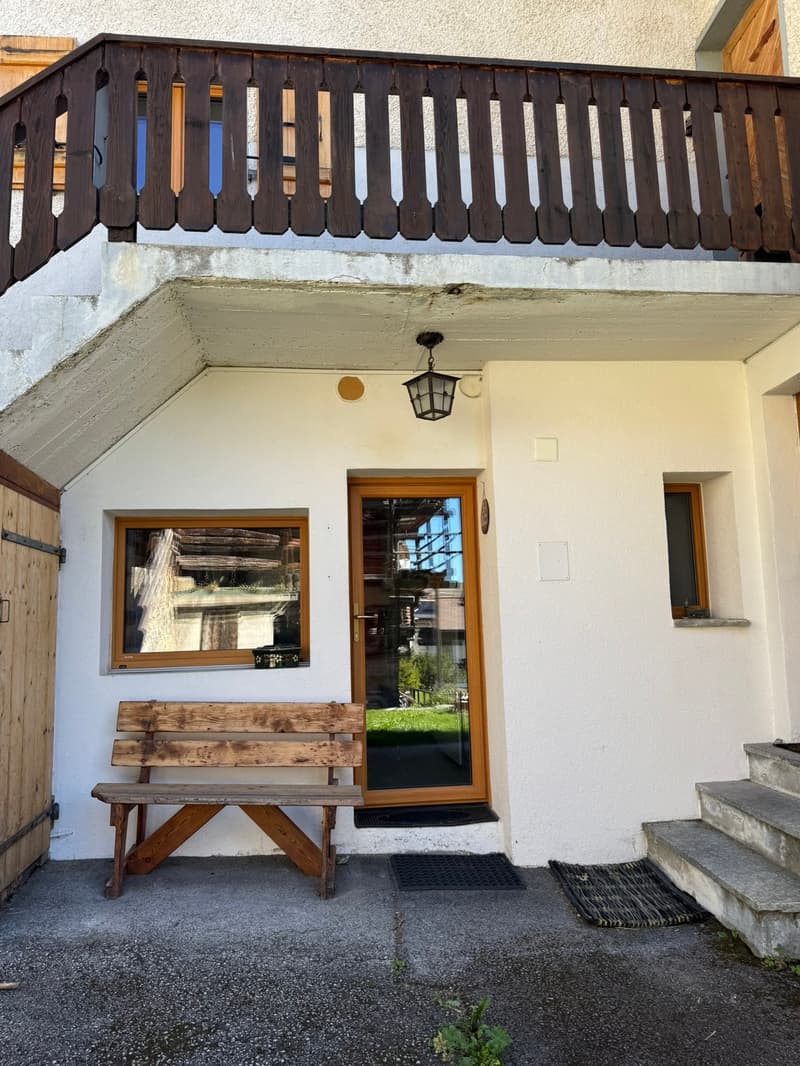 Raised ground floor house, balcony, bench, wooden door, glass door, windows, white walls, steps