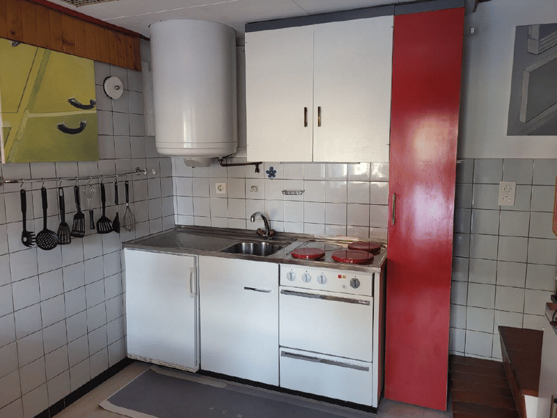 kitchen, sink, stove, kitchen cabinets, countertop, wall mounted art, power outlet