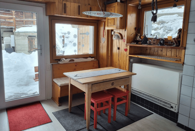 Wooden table and chairs, wooden benches, radiator, snow view from windows, carpet