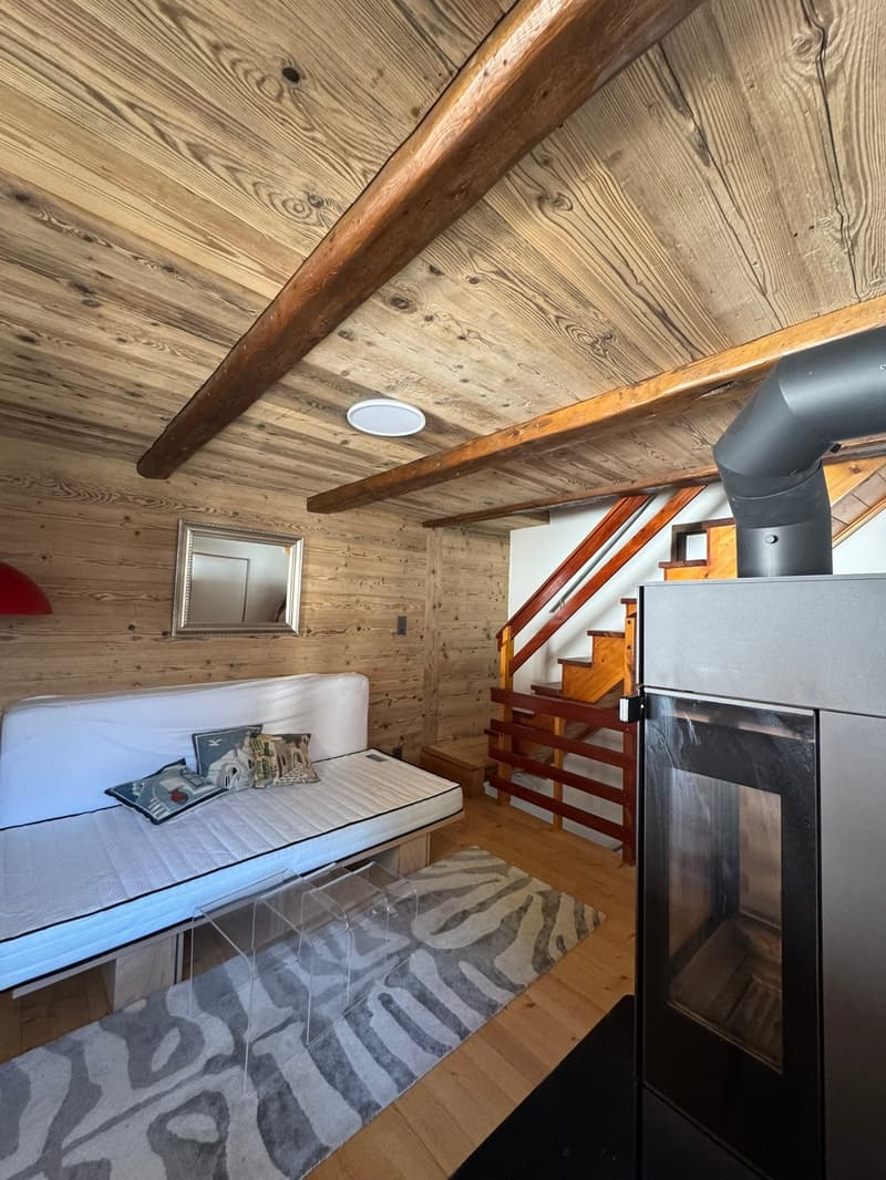 fireplace, exposed wooden beams, cozy sofa, decorative pillows, zephyra rug, wooden staircase