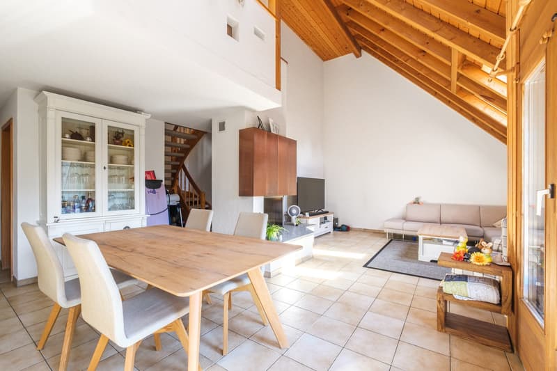 Dining room with wooden table and chairs, wooden cabinets, a wooden cabinet with glass doors, a fireplace, a staircase, a flat-screen TV, a sofa, a coffee table, and a rug
