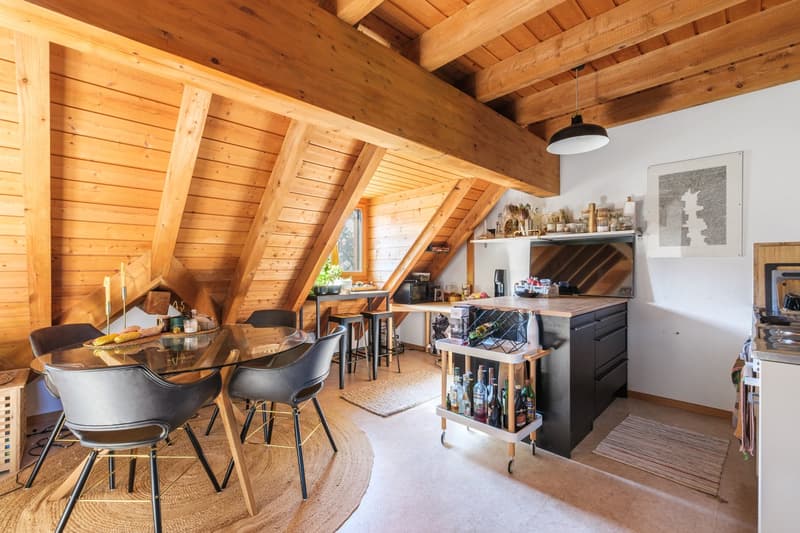 glass table, 6 chairs, carpet, wooden beams, kitchen with counter, shelf with plants, microwave, cabinets, bottles