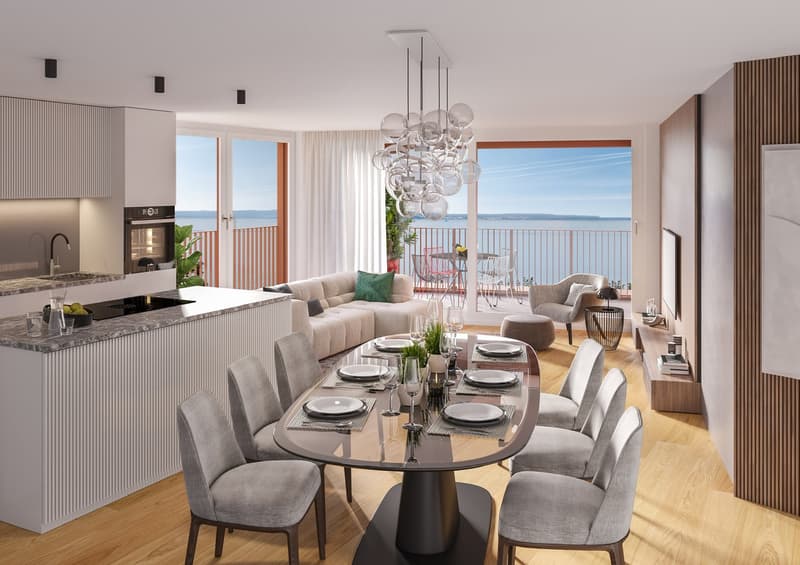 A modern open plan kitchen and dining area, with a view of the sea, featuring a large oval dining table with chairs, a modern chandelier, and a balcony with a table and chairs.
