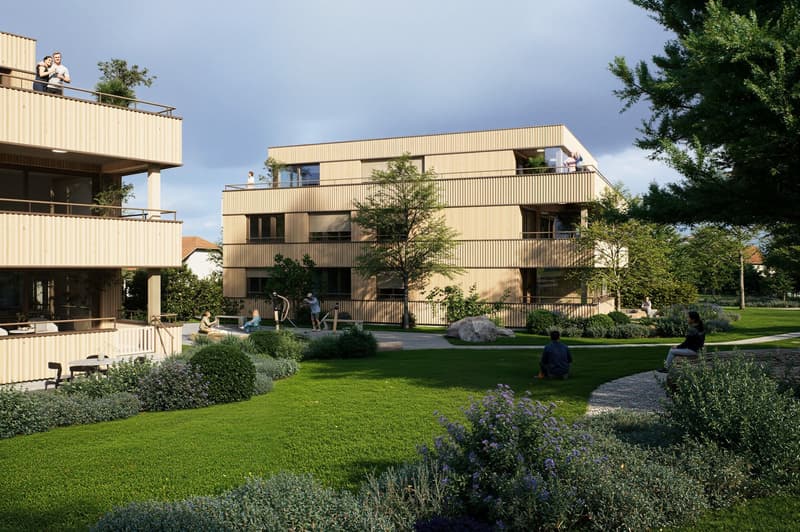 Modern apartment building with balconies, green lawn, trees, and shrubs