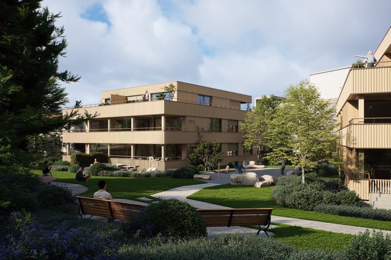 Modern apartment building with balconies, surrounded by greenery and a walkway