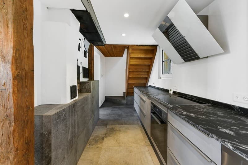 modern kitchen with marble countertops, wooden staircase, white walls, stainless steel appliances