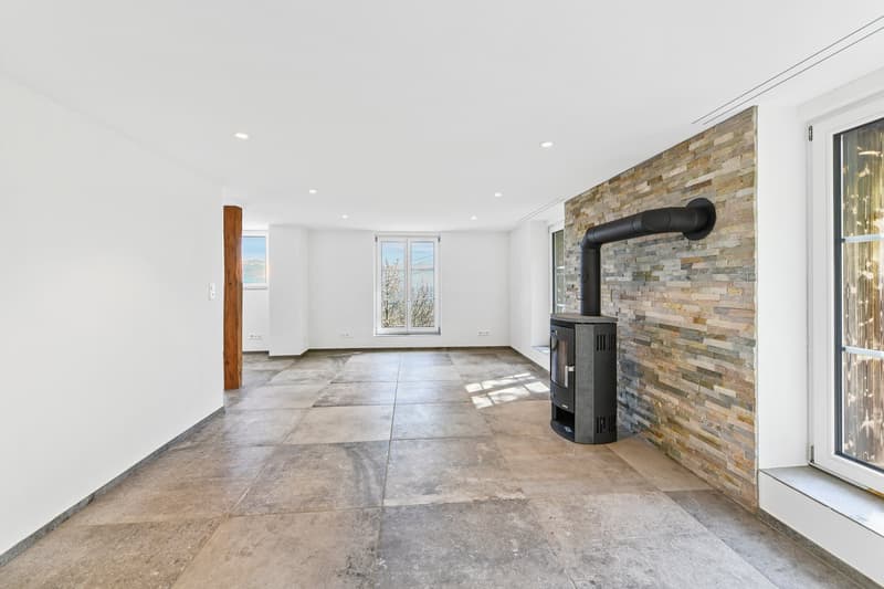 Empty room with fireplace, large windows, wooden pillar, tiled floor