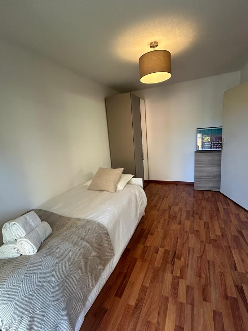 single bed, wooden floor, white walls, light fixture, storage cabinet, wardrobe