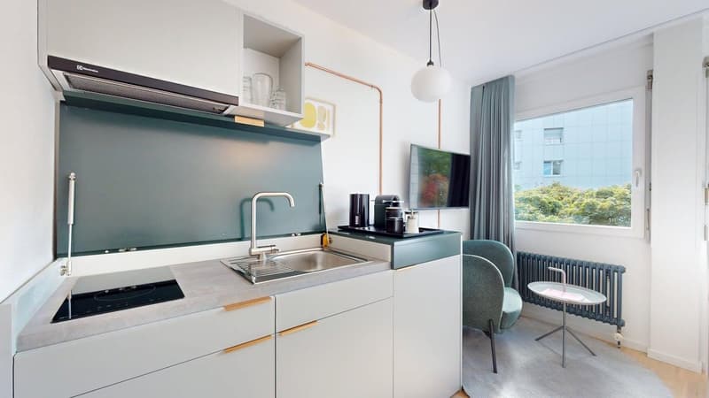 Open plan kitchen, gas stove, stainless steel sink, extractor fan, television, chairs, radiator, windows