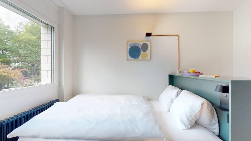 double bed, blue headboard, white walls, glass window, lamp, radiator