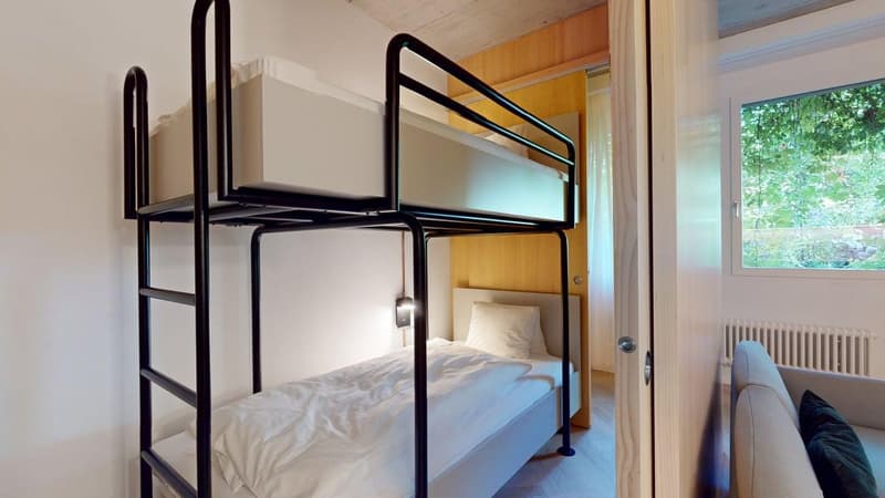double bunk bed with mattress, white pillow, small bedroom with white wall, bed sheet, door, couch, radiator
